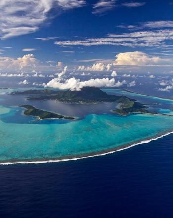 Island surrounded by sand-fringed islets and a turquoise lagoon.