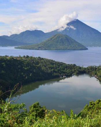 Landscape, water in foreground and green mountains in background.