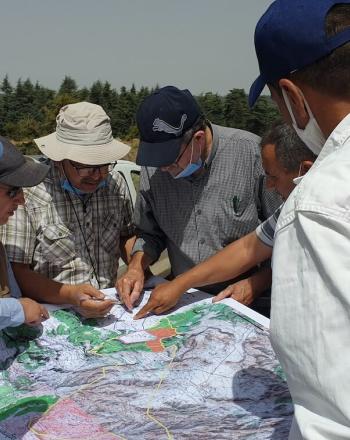 Seis personas afuera paradas alrededor de un mapa, señalando varias partes.