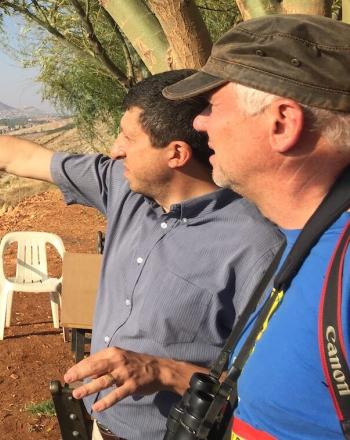 Two men looking in the distance, one pointing.