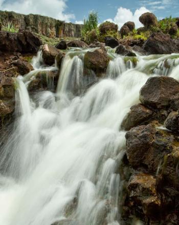 Waterfall against brown rocks.