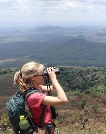 Woman looking through binoculars out at vista