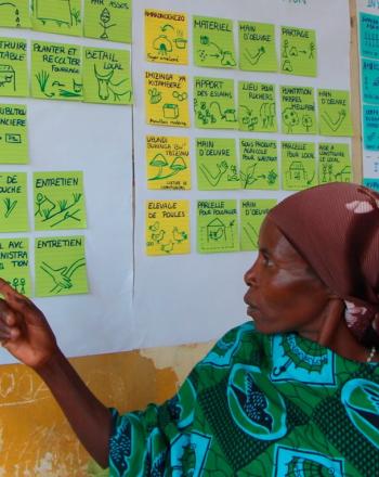 Woman pointing to colorful notes on a wall.