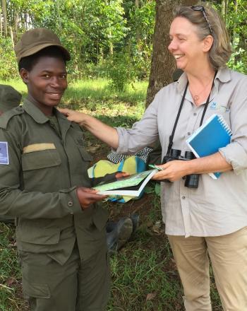 Regional Implementation Team leader stands smiling with marsh ranger and more marsh rangers sit behind them