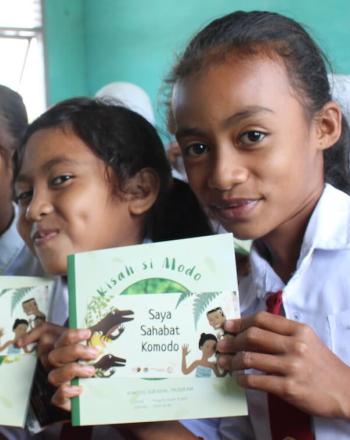 Five girls holding Komodo dragon educational books.