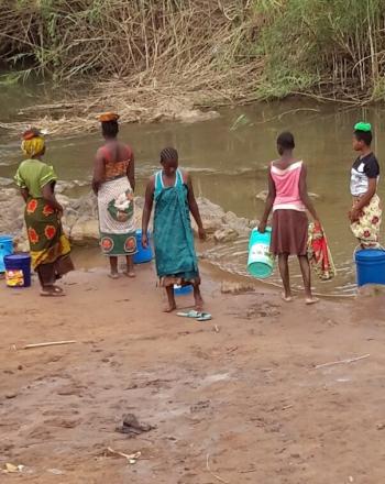 Six women washing laundry along the riverside.