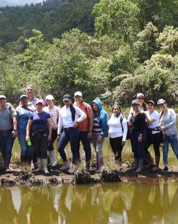 Grupo de un par de docenas de personas de pie en una pequeña franja de tierra con agua a ambos lados, todos frente a la cámara,