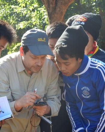 Group of about 7 looking at a handheld monitoring device. 