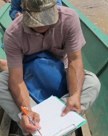 Hombre en canoa escribe en cuaderno.