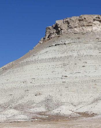 Small, rocky mountain against blue sky.