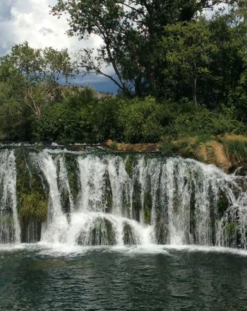 Small, long waterfall amidst greenery.