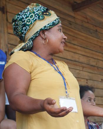 Woman stands, presenting to small group.