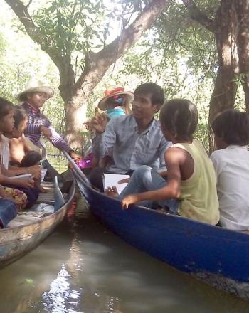 Niños y profesor en dos canoas de madera.