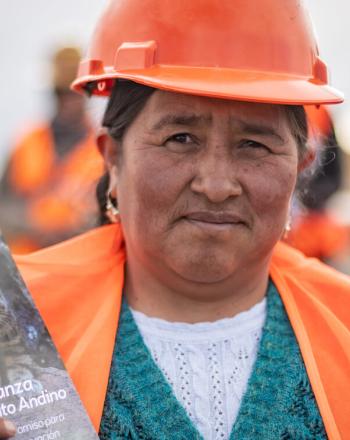 Mujer con casco naranja y chaleco sosteniendo panfleto informativo