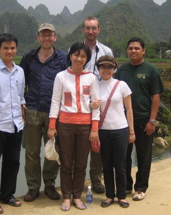 Group of people standing, smiling at camera.