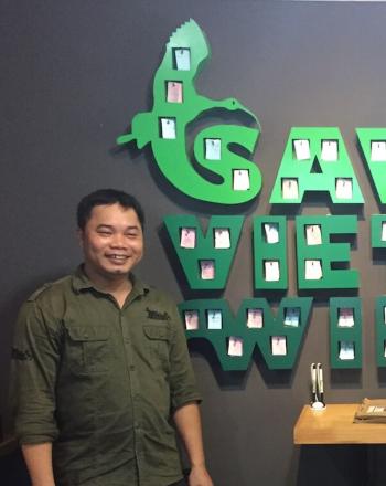 Man standing next to large, green indoor wall sign that reads "Save Vietnam's Wildlife."