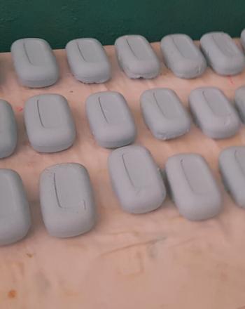 27 bars of gray soap laid out on a table.