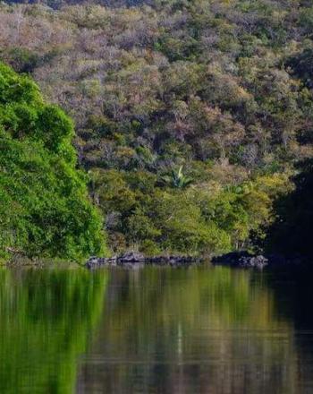 Dark river surrounded by green and brown hills.