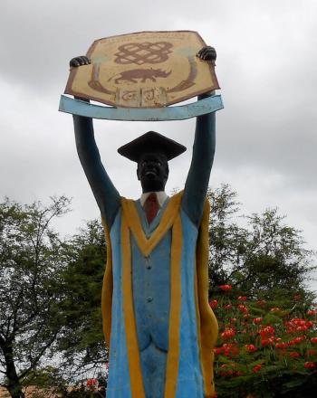 Large statue of graduate holding up sign.