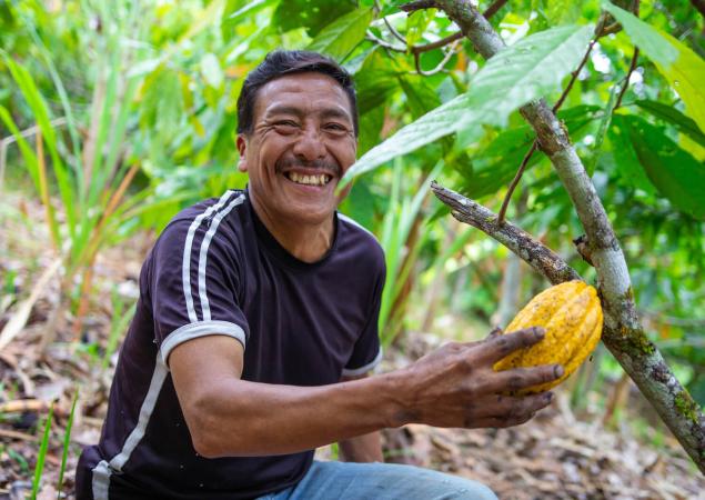 Man smiles at camera, holds up large, yellow seed.