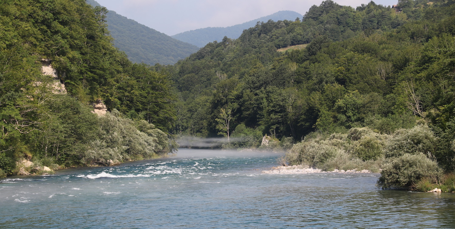 Río, colinas cubiertas de árboles a ambos lados.