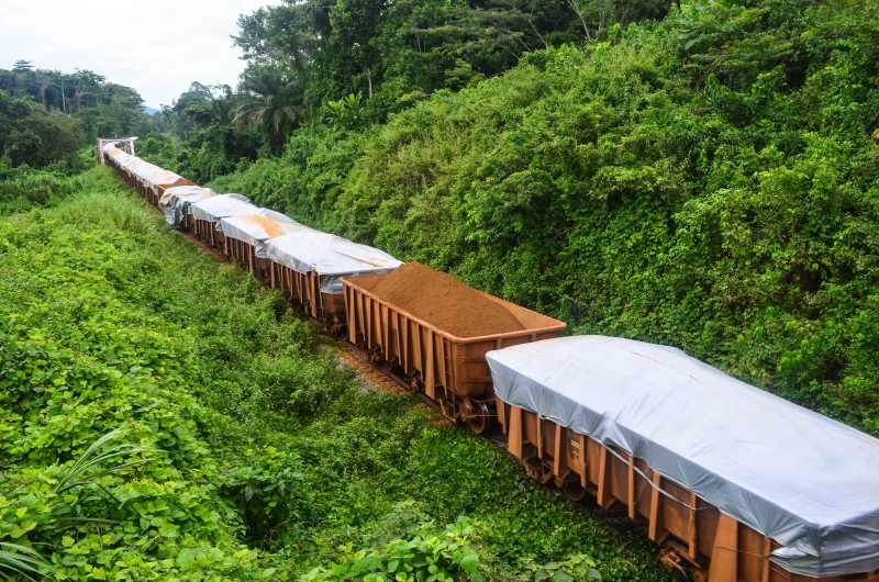 Train heading down tracks with cars filled to the top with iron ore.