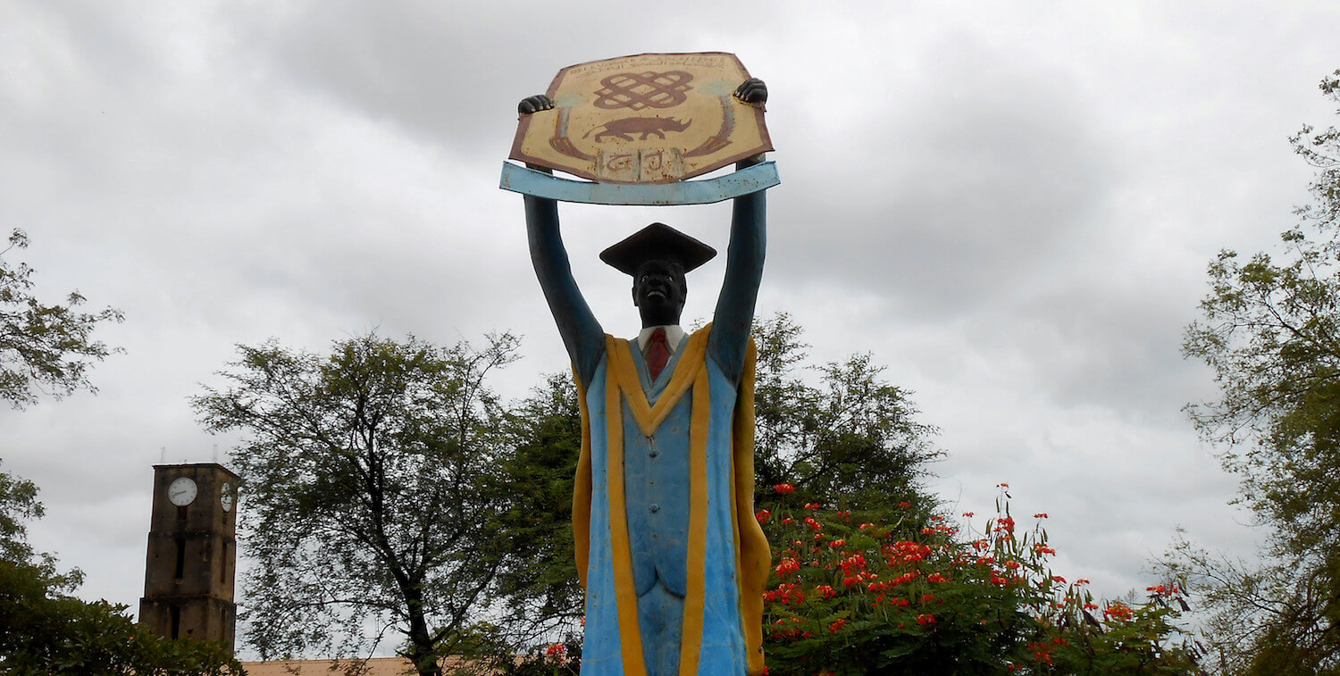 Large statue of graduate holding up sign.